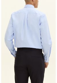 Ljusblå långärmad skjorta med ryggpanel, knappribbor och en slät finish, kombinerad med mörka byxor, vilket ger en formell look.