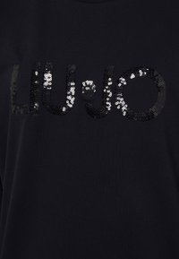 Sudadera de algodón negra con un logo texturizado y con lentejuelas "LIU JO" en plata. Las lentejuelas están dispuestas en diferentes tamaños para dar detalle y brillo.