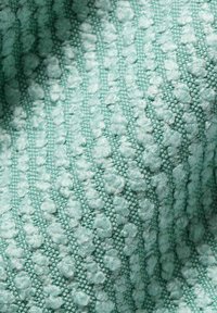 Close-up of light teal fabric with raised textured loops arranged in diagonal rows creating a soft, patterned surface.