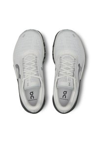 Des chaussures de sport Cloudmonster en maille blanche avec des accents gris, présentant une tige texturée, des lacets ronds et une semelle épaisse noire.