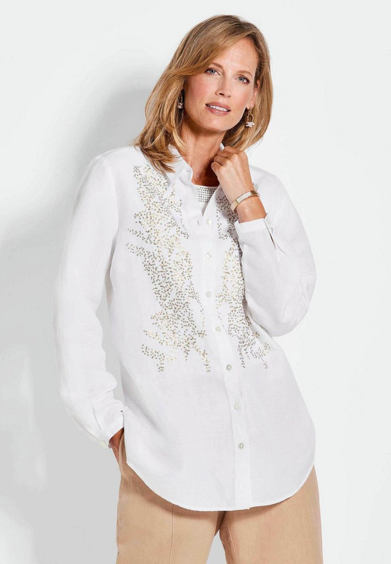 Weißes Button-Down-Hemd mit aufwendigen goldenen Verzierungen, langen Ärmeln, einem Kragen und einem leicht geschwungenen Saum. Leichter Stoff.