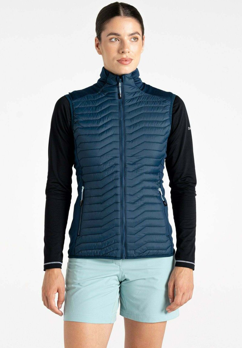 Dunkelblaues isoliertes Weste mit Zickzacknähten, hohem Kragen, Reißverschlusstaschen und slim Fit, getragen über einem schwarzen Langarmoberteil.