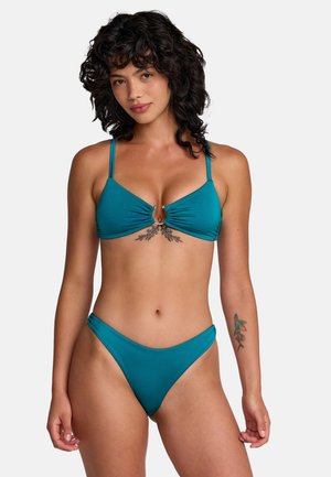 Ensemble bikini bleu sarcelle comprenant un haut triangle avec fronces à l'avant et détail anneau en métal. Le bas est taille basse avec une finition lisse.