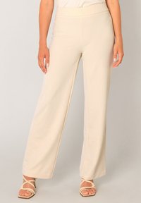 Beige wijde broek met een soepele textuur en een elastische tailleband, voorzien van een verfijnde piping langs de naden.