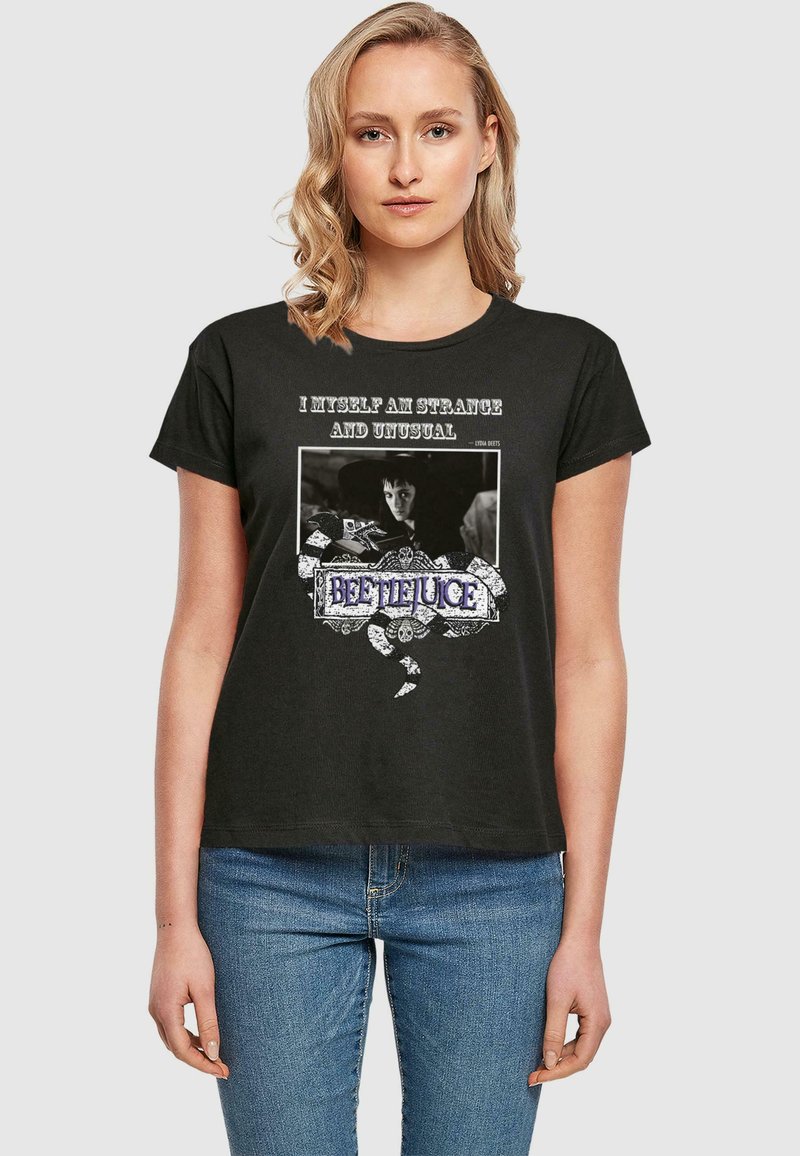 Svart bomull T-skjorte med grafisk trykk som har teksten "Jeg er selv merkelig og uvanlig" og et dekorativt "Beetlejuice" design.