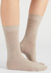 Beige katoenen sokken met een gebreide textuur, midden kuitlengte, en een geribbelde boord. Eenvoudig ontwerp zonder patronen of extra accenten.