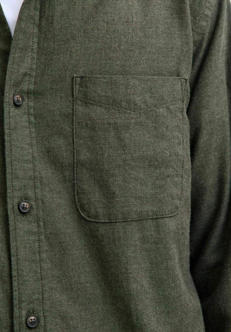 Grünes, strukturiertes Hemd mit Brusttasche und dunklen Knöpfen, aus weichem Stoff und mit klassischem Kragen-Design.