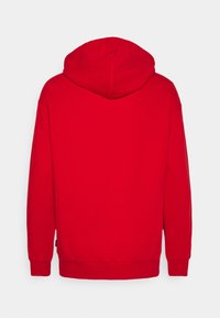 Sudadera roja con capucha ajustable, mangas largas y dobladillo acanalado. La tela tiene una textura suave sin logotipos ni patrones visibles.