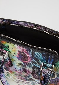 Kolorowa torebka z teksturą imitującą skórę węża w odcieniach fioletu, zieleni i czerni. Srebrne okucia z łańcuszkowym akcentem.