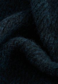 Teren de țesătură texturată, de un albastru închis, cu o suprafață moale și pufoasă, evidențiind o combinație de nuanțe adânci și fibre vizibile, creând un aspect bogat și stratificat.
