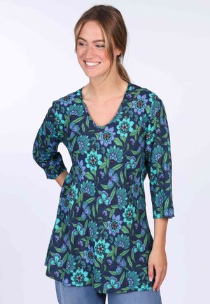 Floral tunic top with a V-neck, featuring a navy background, green leaves, and vibrant blue flowers, made from lightweight fabric.