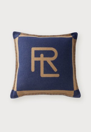 Coussin bleu marine avec une bordure beige, présentant un logo doré bien en vue. Texture de tissu douce avec des coutures contrastantes le long des bords.