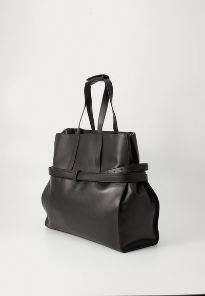 Black leather tote bag with open top, long handles, and a wide base. Features a belt-like strap around the middle for added detail.