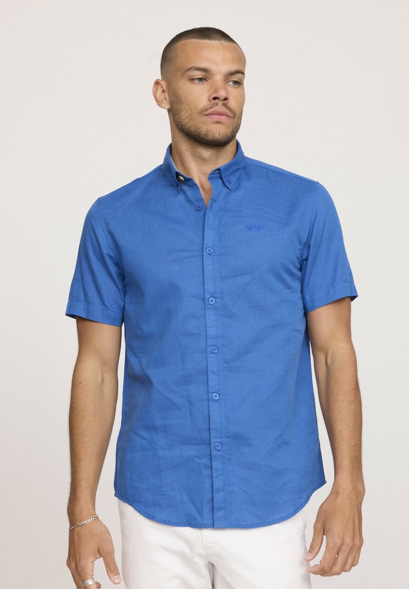 Chemise à manches courtes bleu, en tissu texturé, avec un col et six boutons sur le devant.