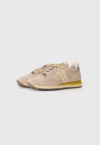 Sneakers in suede beige con suola in gomma, caratterizzati da accenti gialli, dettagli grigi e una sovrapposizione in rete. Design con lacci e silhouette classica.