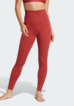 High-waisted leggings made of stretchy, smooth fabric in a rich rust color. Features minimalist design with no visible patterns or accents.