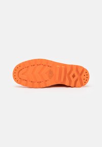 Suela de zapatilla de goma de color naranja brillante con patrones de agarre texturizados y tres crestas distintas. Cuenta con agujeros de drenaje para la liberación de agua.