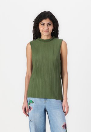 Ermeløs grønn topp med vertikale folder, høy krage og myk tekstur. Kombinert med lyseblå jeans med blomsterbroderi.