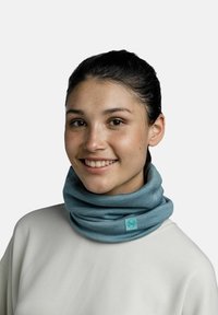 Light blue multifunctional neck gaiter made of soft fabric, featuring a brand tag. Worn comfortably around the neck.
