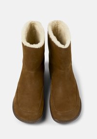 Hnědé semišové kotníkové boty s měkkou krémovou fleecovou podšívkou, které mají hladký povrch a zaoblený design špičky.