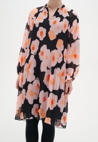 Plisserad klänning med långa ärmar i svart bakgrund och stora rosa och orange blommönster. V-ringning och samlade manschetter vid ärmarna.