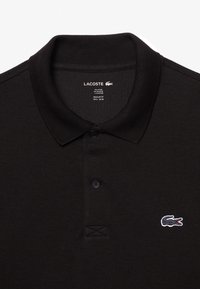 Schwarz Polo-Shirt aus Baumwolle und Polyester, mit einer Knopfleiste mit zwei Knöpfen, gesticktem Krokodil-Logo und geripptem Kragen und Saum.
