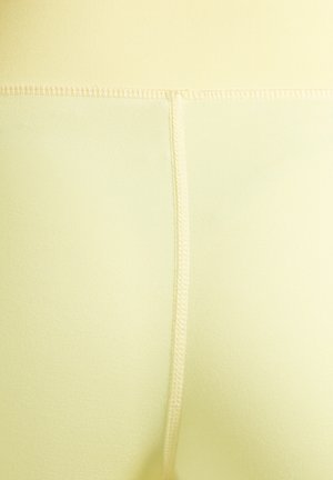 Gele legging met een gladde textuur, voorzien van een hoge tailleband en platte naden voor comfort. De stof lijkt elastisch en nauwsluitend.