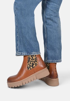 Stivali ankle in pelle marrone con pannelli laterali in stampa leopardata e suola texturizzata color tan; caratterizzati da un design a piattaforma chunky.