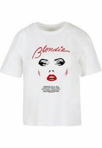 Valge puuvillane T-särk, millel on graafiline trükk näost, kus on julged mustad silmad ja punased huuled, ning tekst "Blondie" punases kalligraafias peal.