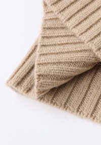 Beige knitted fabric with a ribbed texture. Close-up shows detailed stitching and a soft, fuzzy appearance.