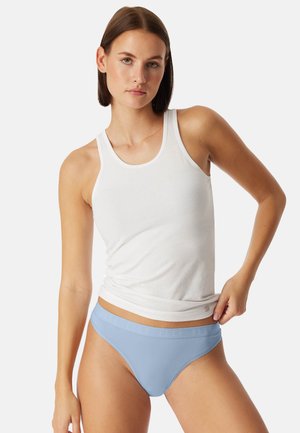 Ljusblå bikiniunderkläder med en mjuk, elastisk midjeresår och en slät yta. Bärs med en åtsittande vit linne.