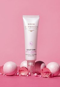 Grow Gorgeous B3 Pielęgnacja Skóry Głowy w białej tubie ze złotym napisem, otoczona różowymi i srebrnymi kulkami w różnych rozmiarach, na różowym tle.