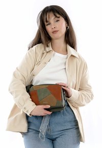 Patchwork handtas met tinten bruin, groen en tan. Rechthoekige vorm, vervaardigd van getextureerd leer, voorzien van een ritssluiting.