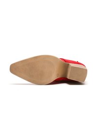 Zapato perforado rojo con punta redondeada, suela de goma y una suela exterior suave y de color claro que presenta estrías horizontales para mayor tracción.