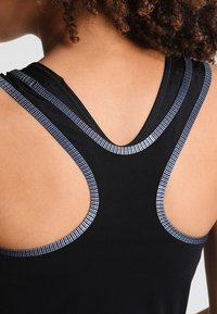 Débardeur de sport noir avec de fines rayures bleu marine le long du dos nageur et de l'encolure, texture de tissu lisse avec une coupe ajustée.