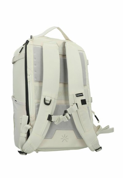 Mochila de color beige claro con un diseño estructurado, que presenta correas ajustables acolchadas, un bolsillo frontal con cremallera y acentos de malla para ventilación.