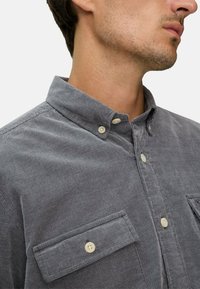 Grau karierter Hemd aus strukturiertem Stoff, mit umschlagbarem Kragen, zwei Brusttaschen und hellen Knöpfen.