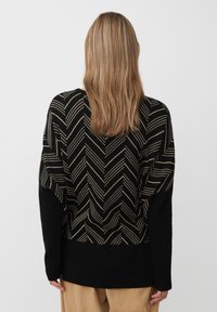 Zwart truitje met gouden chevronpatroon, textuurgebreid, verlaagde schouders en ribgebreide mouwen. Eenvoudige, casual pasvorm met een effen achterkant.
