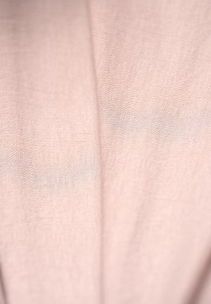 Jasnoróżowa tkanina o miękkiej strukturze, z delikatnym połyskiem i lekkimi detalami fałd, odpowiednia do odzieży lub akcesoriów.