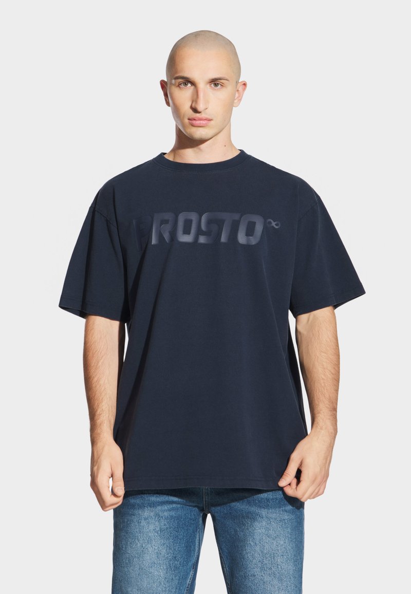 Granatowa bawełniana koszulka z wyrazistym, tonalnym logo "PROSTO" na klatce piersiowej. Luźny krój, krótkie rękawy i okrągły dekolt.