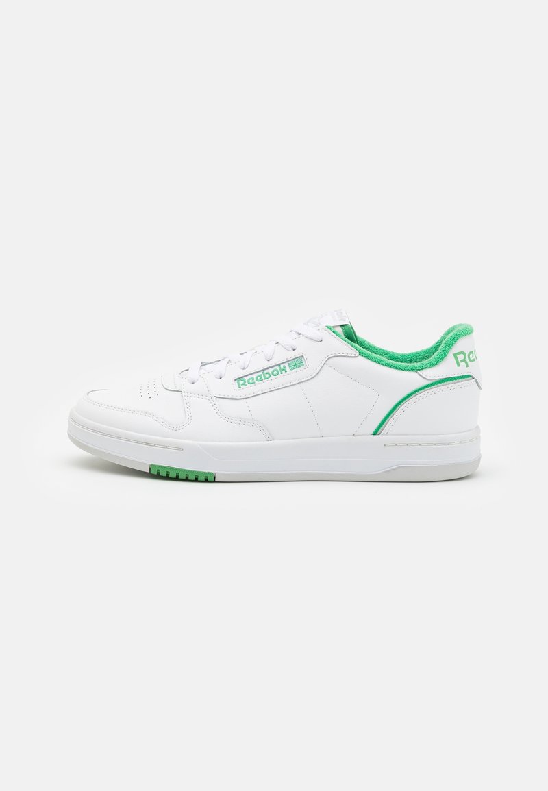 Baskets basses blanches Reebok avec doublure intérieure verte, logo vert sur le côté, détail vert au talon et lacets blancs sur fond blanc.