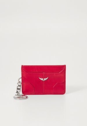 Red leather card holder with a smooth texture, featuring a silver wing accent and a detachable chain for attachment. Compact rectangular design.