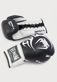 Ασπρόμαυρα γάντια πυγμαχίας με γυαλιστερό φινίρισμα. Διαθέτουν κορδόνια για δέσιμο, λεπτομέρειες με λογότυπο και επένδυση υποστήριξης στον καρπό.