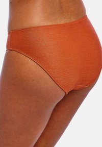 Oranžové plavkové kalhotky z boku, s hladkým povrchem a jemným leskem, mají vysoký střih nohavic a minimální švy.