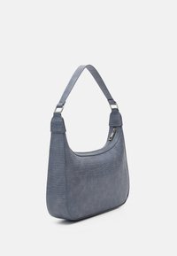 Niebieska torebka z teksturą krokodyla o zaokrąglonym kształcie i szerokim pasku na ramię; posiada srebrne elementy metalowe oraz zamek błyskawiczny wzdłuż górnej części.