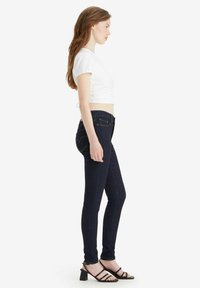 Vaqueros skiny azul oscuro hechos de denim, con una textura suave, diseño clásico de cinco bolsillos y sutiles detalles de costura.