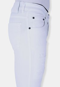 Witte denim jeans met een aansluitend ontwerp, versleten details op het bovenbeen en zwarte bloemaccenten op de achterzakken.