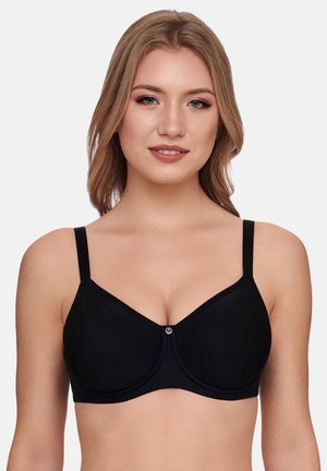Young woman with light brown hair wearing a black underwire bra with adjustable straps, facing forward against a plain background.