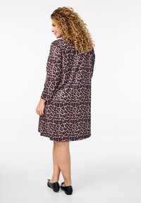 Abito a stampa leopardata con maniche lunghe e vestibilità rilassata, realizzato in tessuto leggero. Presenta un colletto rotondo e cade sopra il ginocchio.