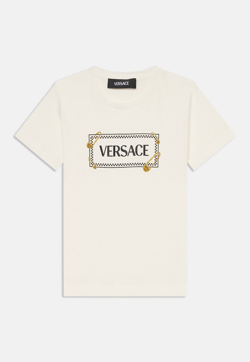 Camiseta de algodón blanca con un logo rectangular negro enmarcado por un borde a cuadros y imperdibles dorados. Cuello redondo y mangas cortas.